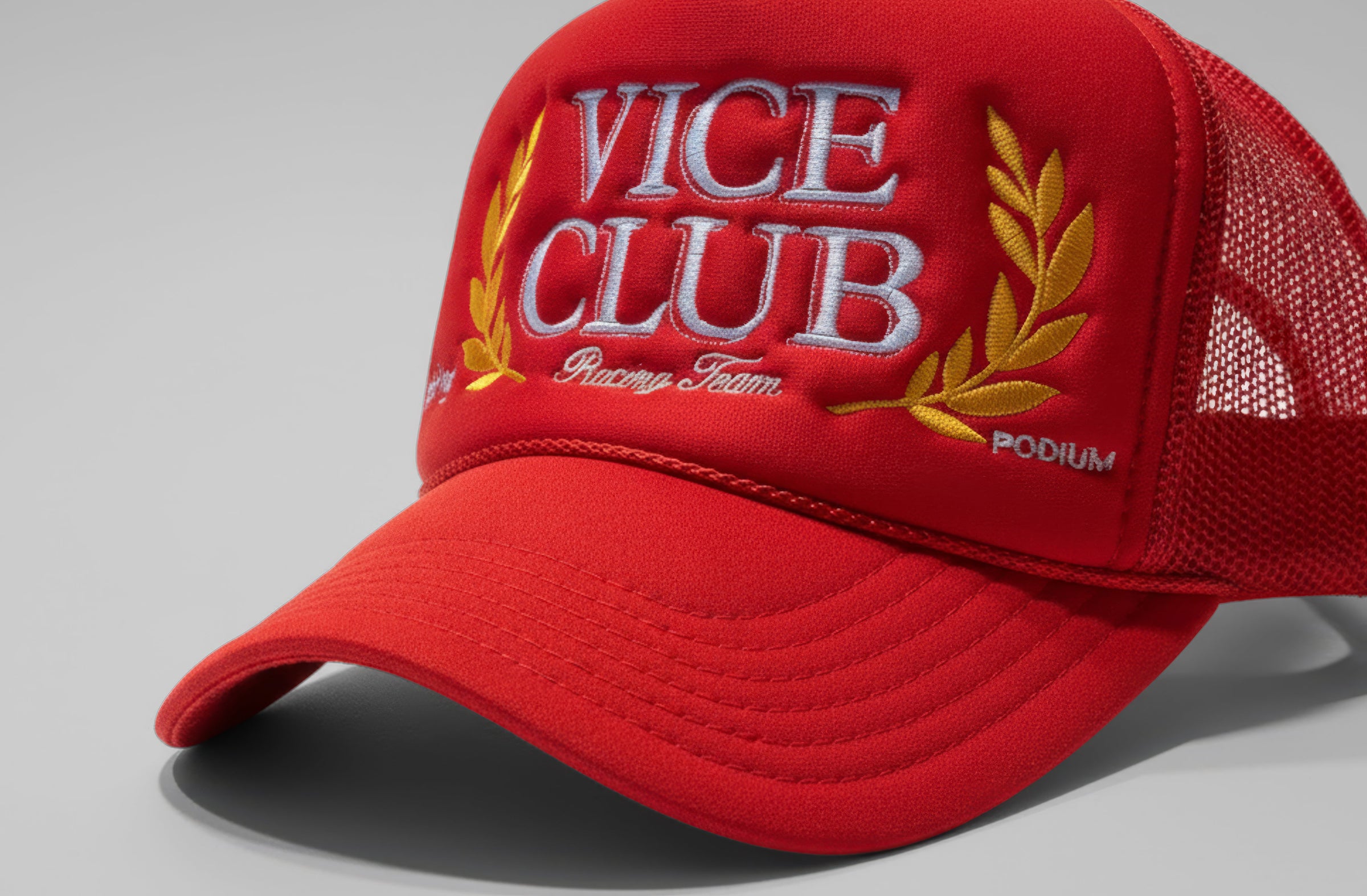 Red Vice Club trucker hat with embroidered logo and laurel detail, premium structured design in minimal studio setting.